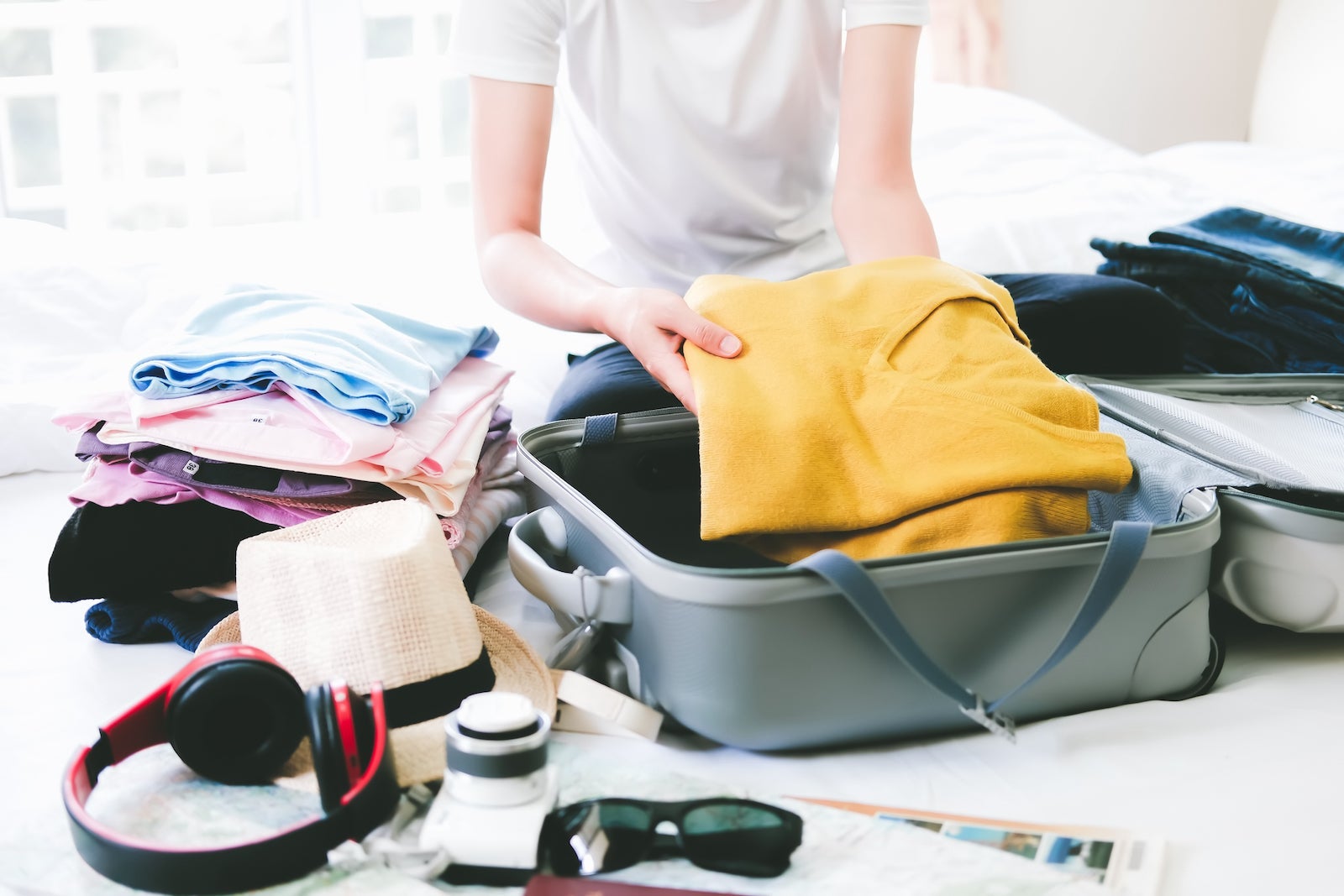 Woman packing suitcase on bed at home