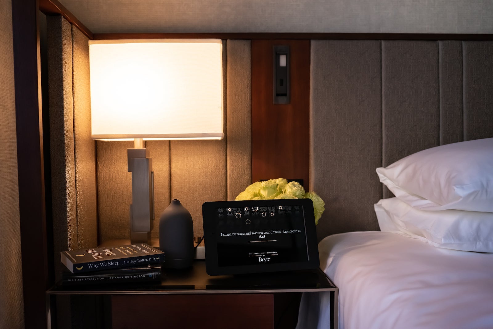 hotel bed and nightstand with iPad controller on nightstand