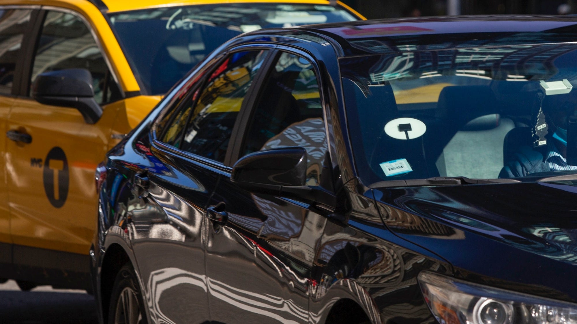 Uber driving in front of a taxi in New York City