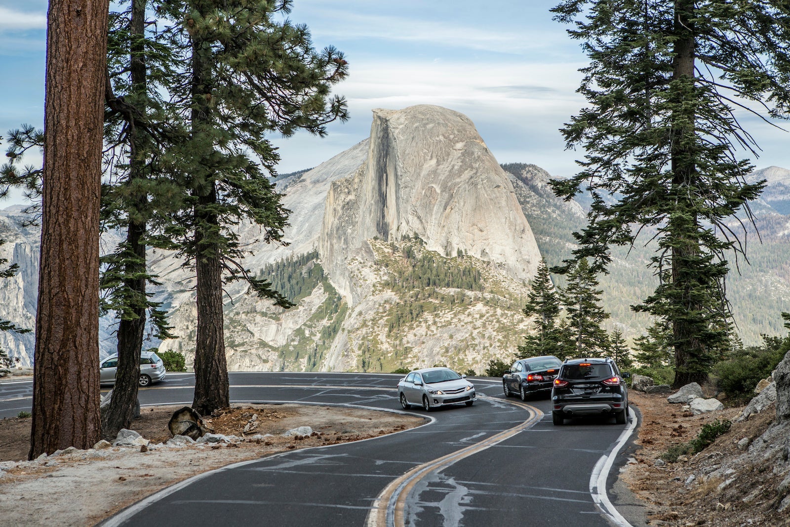 Cars driving down a windy road in Yosemite National Park while on a road trip through the park.