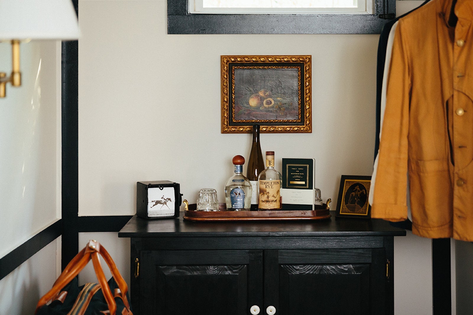 dresser with minibar, hanging jackets, and painting