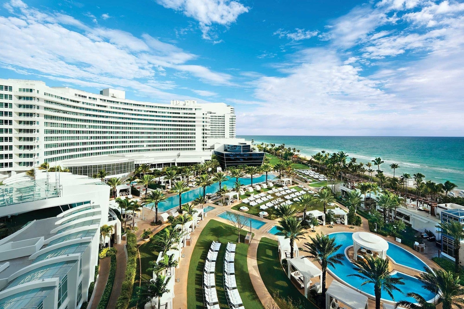aerial photo of large hotel near the beach, swimming pools and lounge chairs