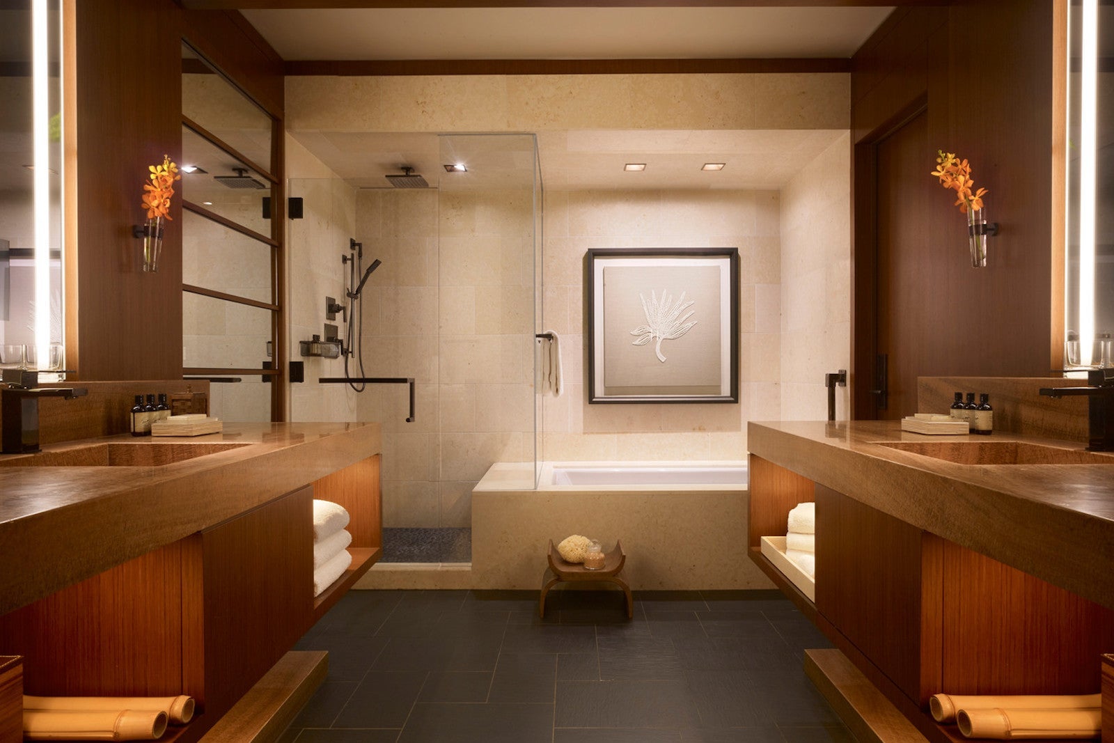 photo of wood-lined bathroom, dark tile floors, a large soaking tub and shower and two vanities back-to-back