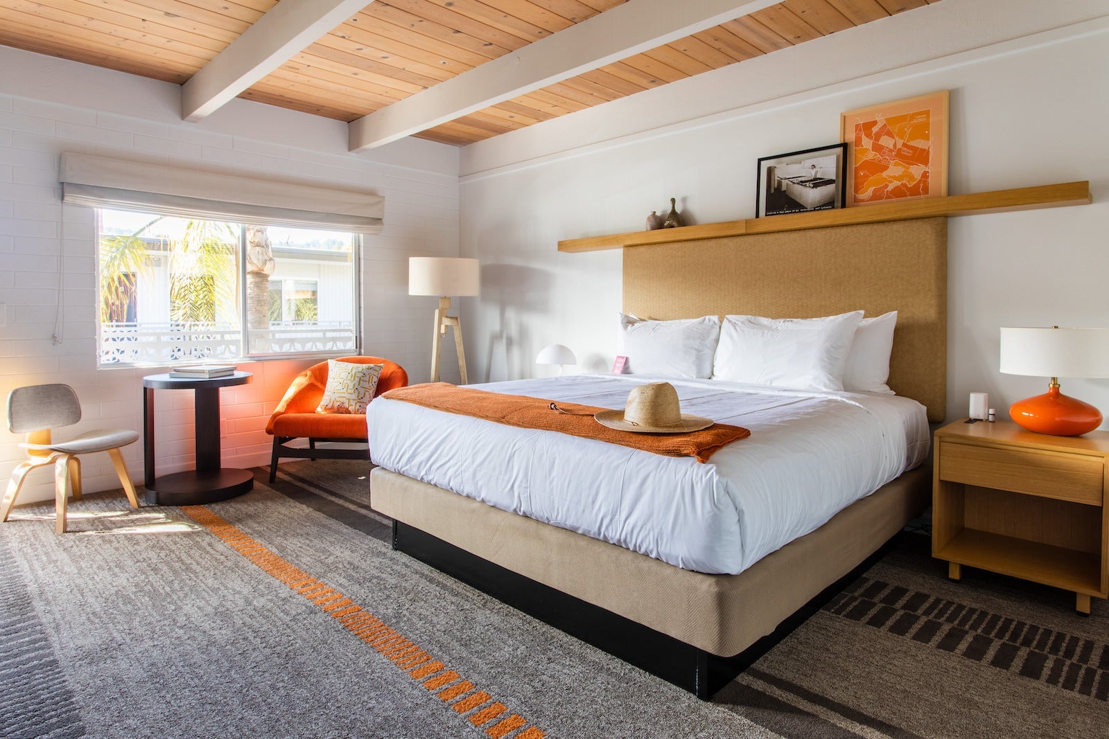 hotel room with wood ceilings, large bed with white sheets and orange chair