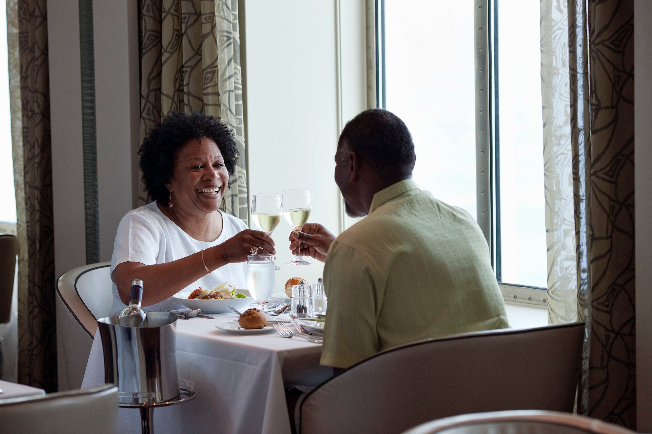 Couple on a cruise ship having dinner near a window in the dining room