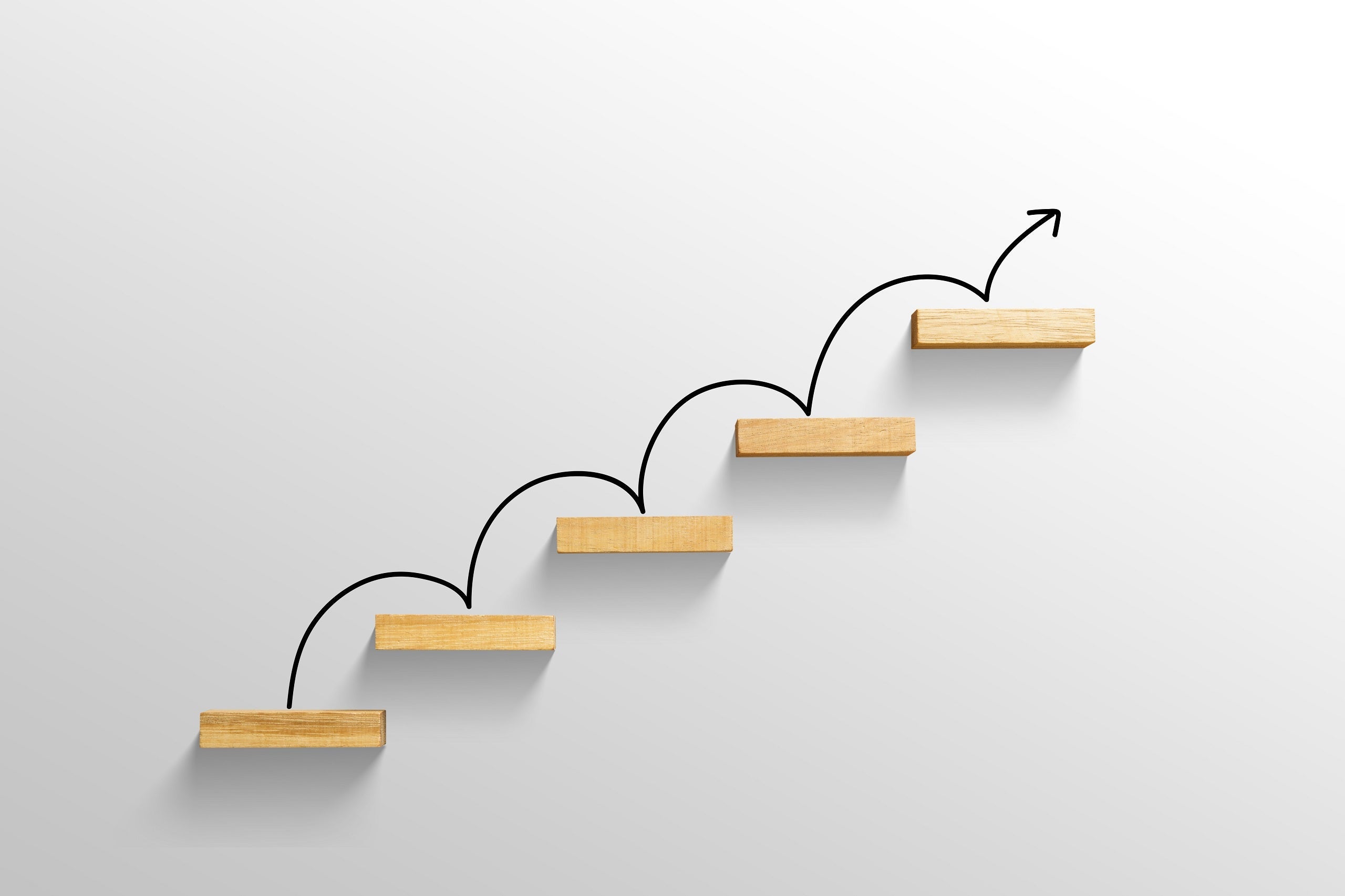 Ascending wooden shelves on a white wall with a black arrow bouncing from one to the next