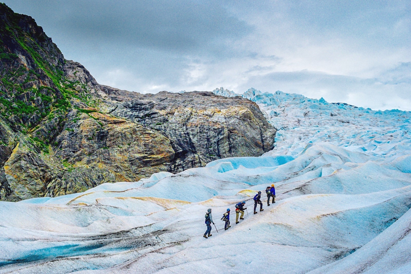 High Angle View Of People Hiking On Snow Covered Mountains Against Sky