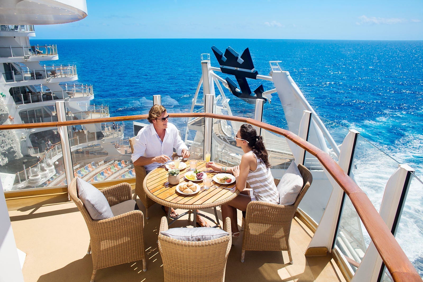 Couple dining on cruise cabin balcony overlooking AquaTheater on Royal Caribbean's Allure of the Seas