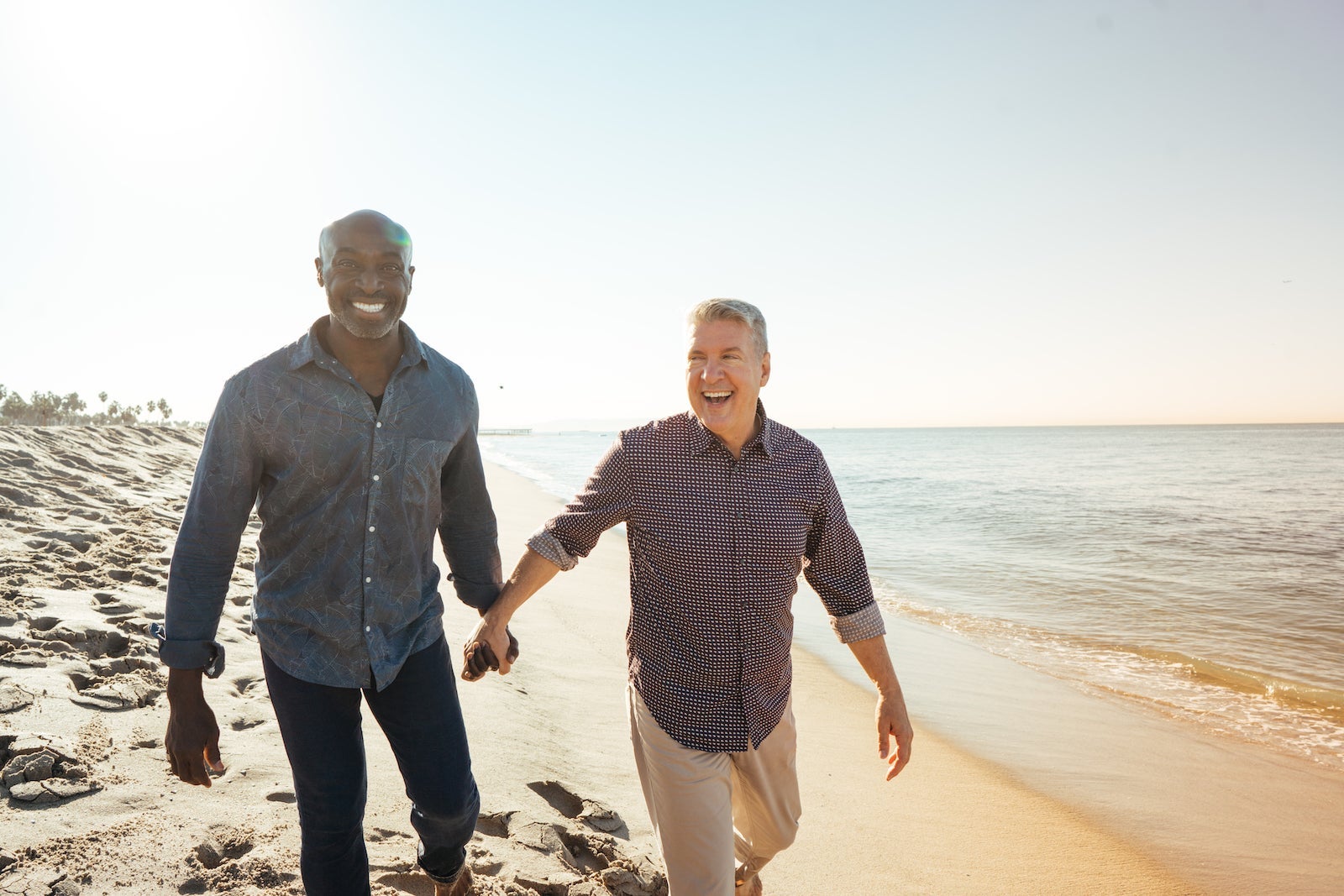 A couple walks hand-in-hand on the beach.