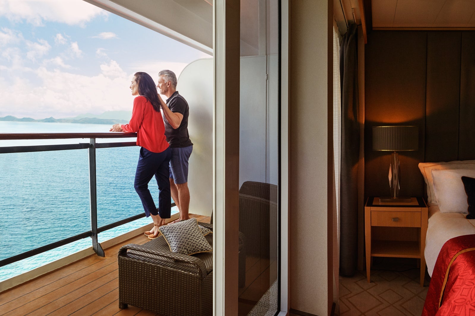 Older couple standing on cruise ship cabin balcony looking out to sea