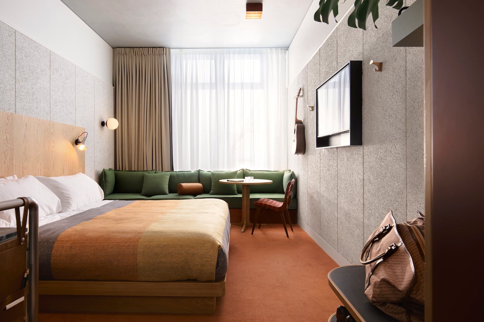 rendering of hotel room with red-orange floor, guitar on wall and hip modern design
