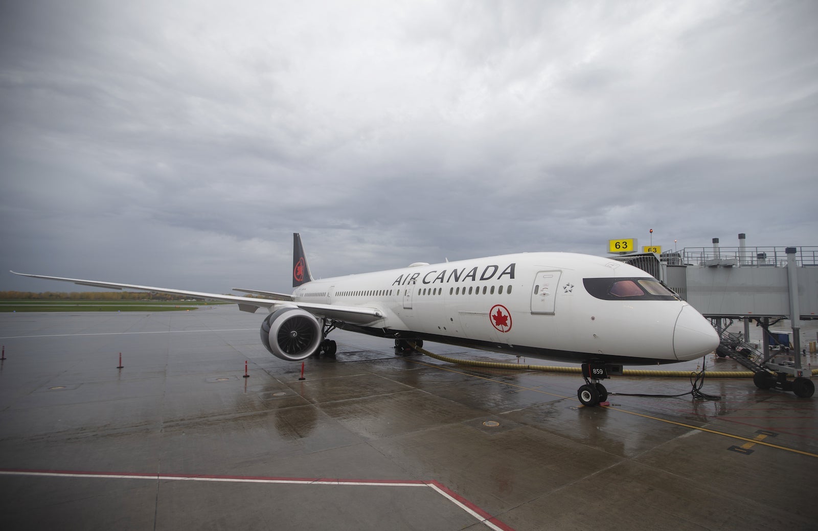 an Air Canada plane sits at a jet bridge under a cloudy sky