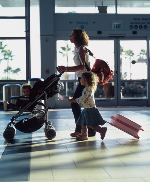 Mom with young daughter and baby in stroller walking through airport