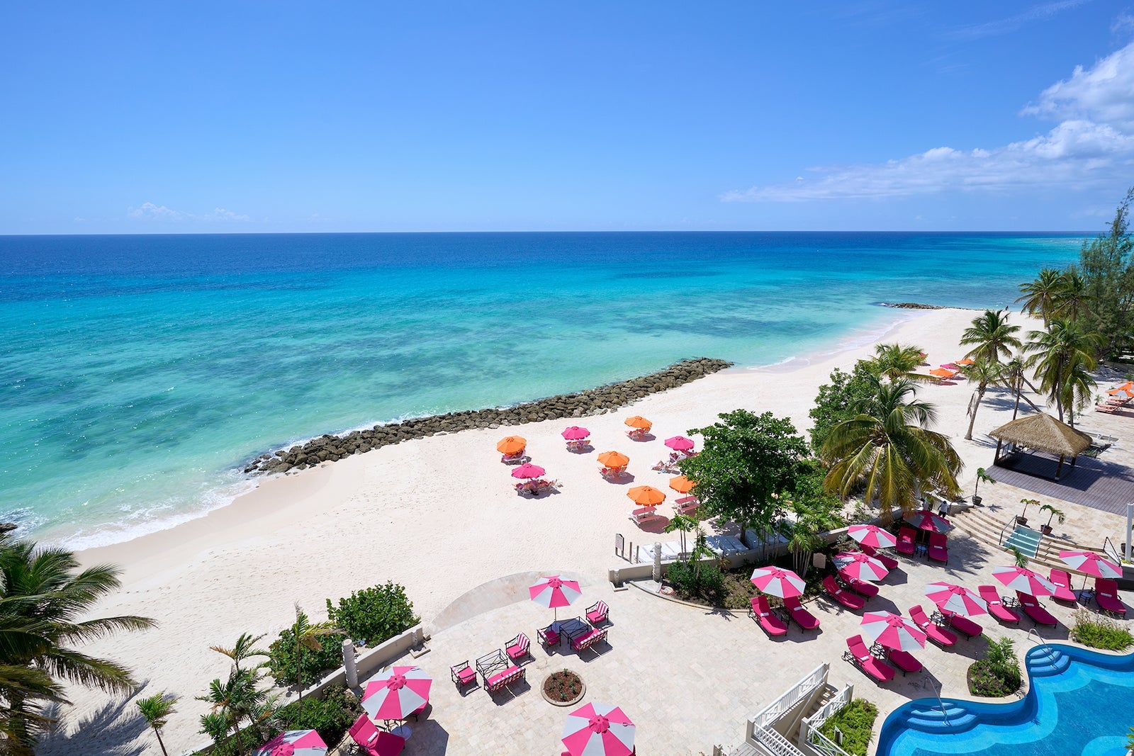 view of white sand beach with pink umbrellas and beach chairs