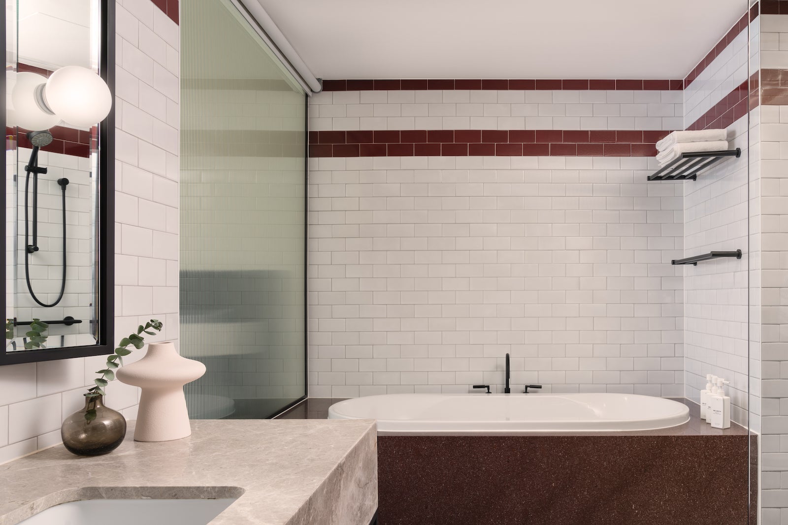 hotel bathroom with large bathtub, white subway tiles and sink
