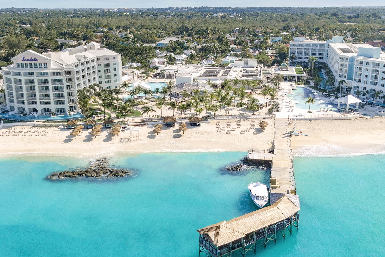 aerial photo of large beach resort, crystal clear blue water and large deck with yacht