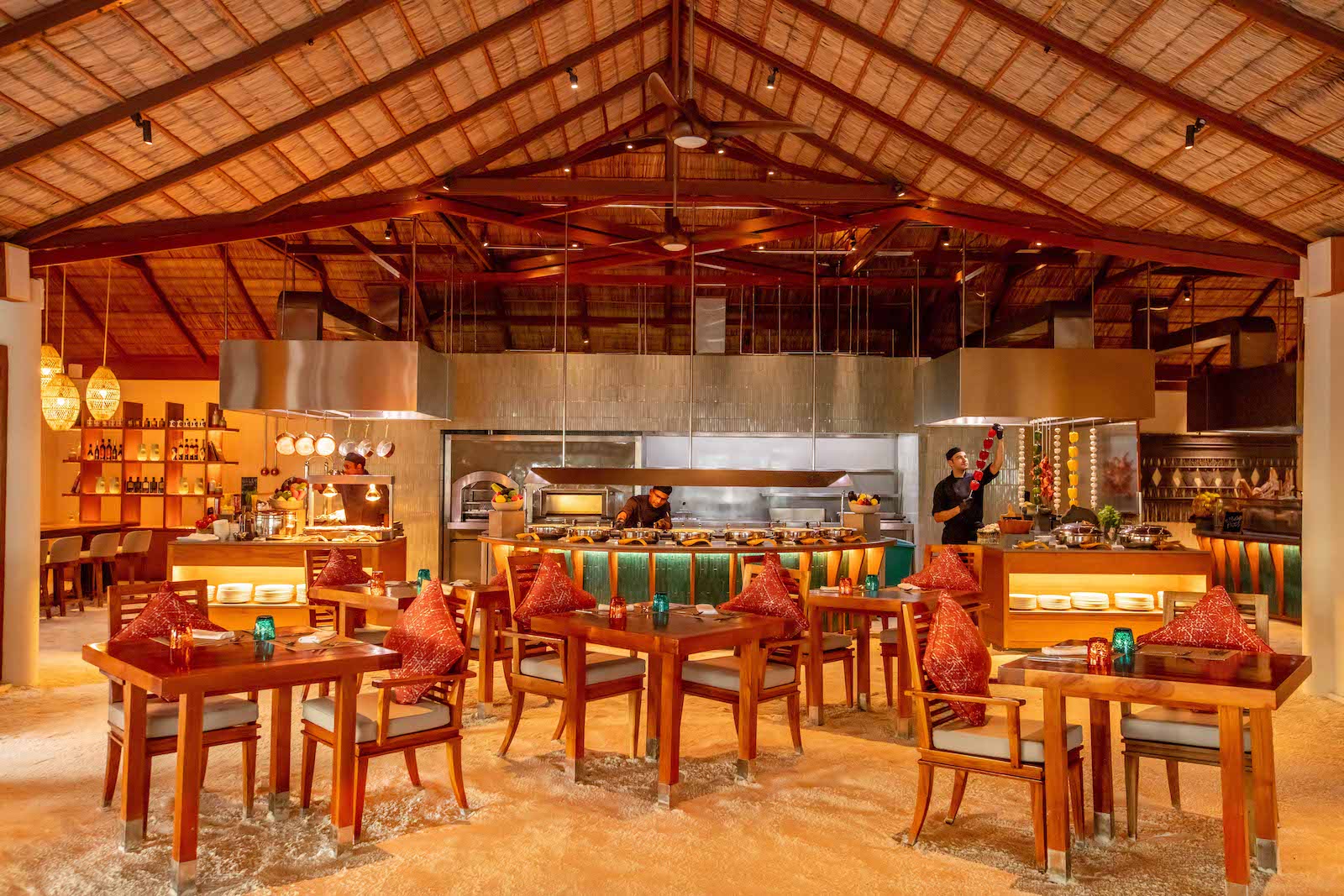 large thatched roof and sand-floor restaurant with tables and cooking stations