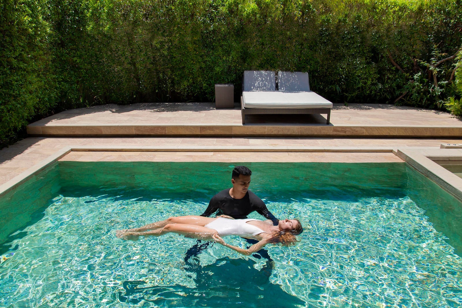 woman floating in pool being held up by man