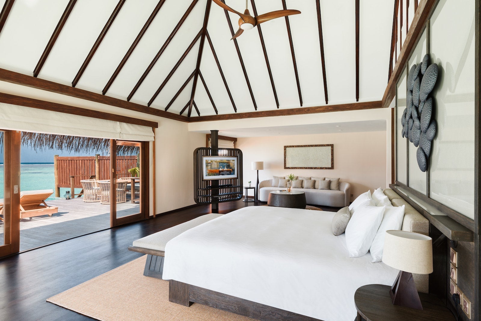 villa with bed looking out at open door to deck over the water