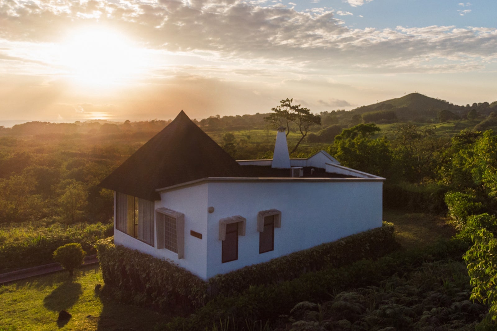 villa on hill surrounded by plants and hills at sunset