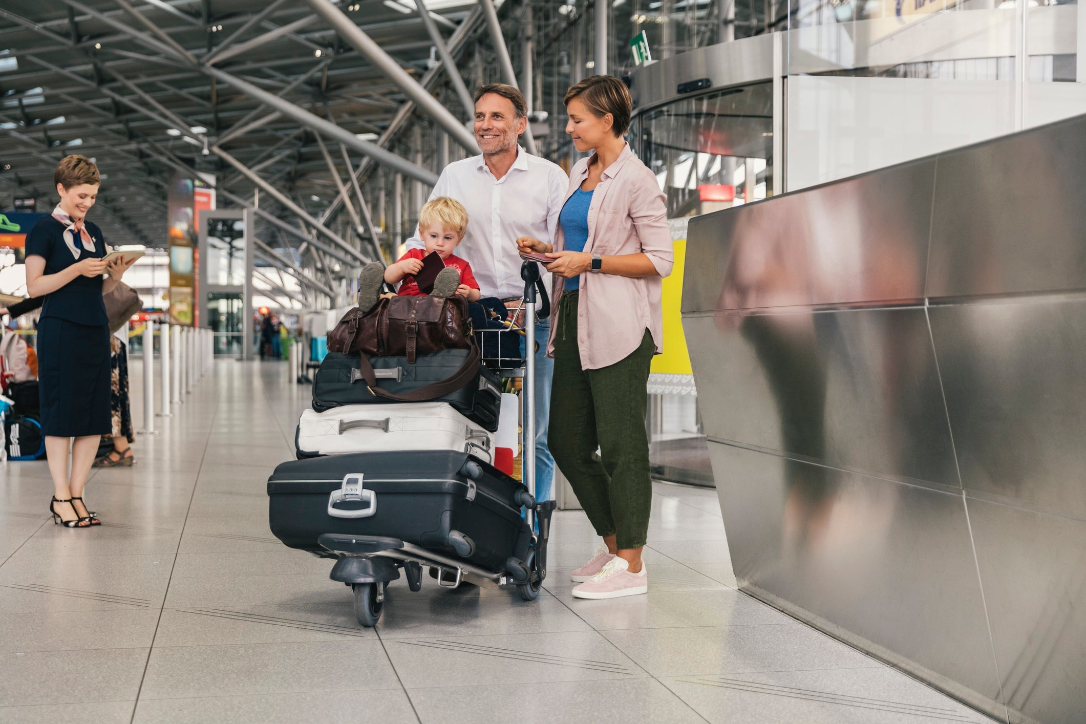 Parents pushing luggage rack with toddler on board