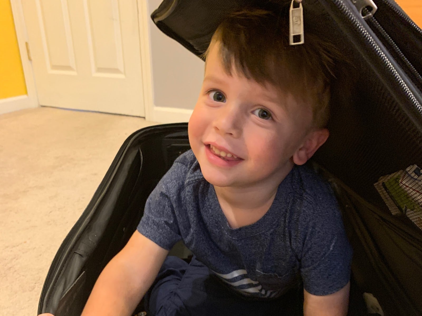 child pretending to climb in suitcase