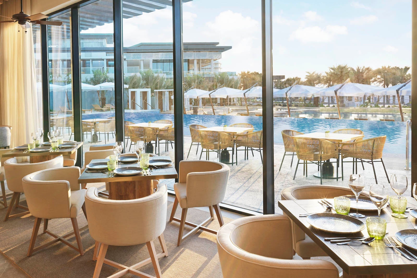 dining room with tables and floor-to-ceiling glass wall looking out at pool