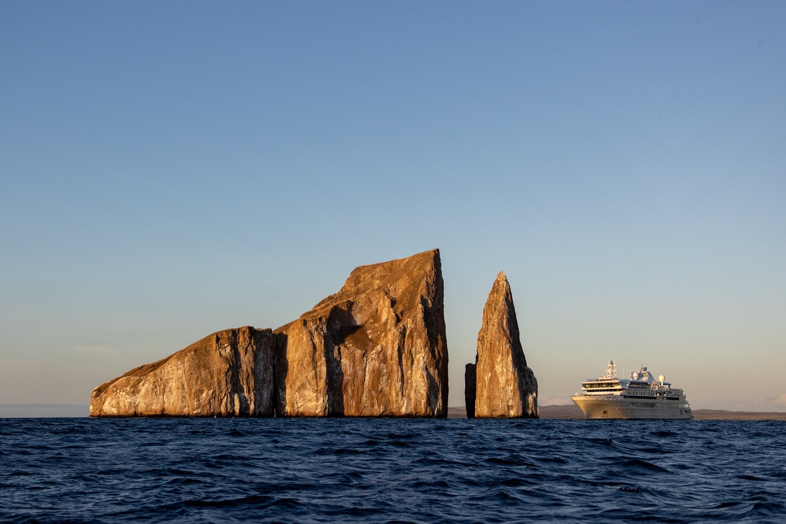 A cruise ship anchored by a rock formation in the Galapagos