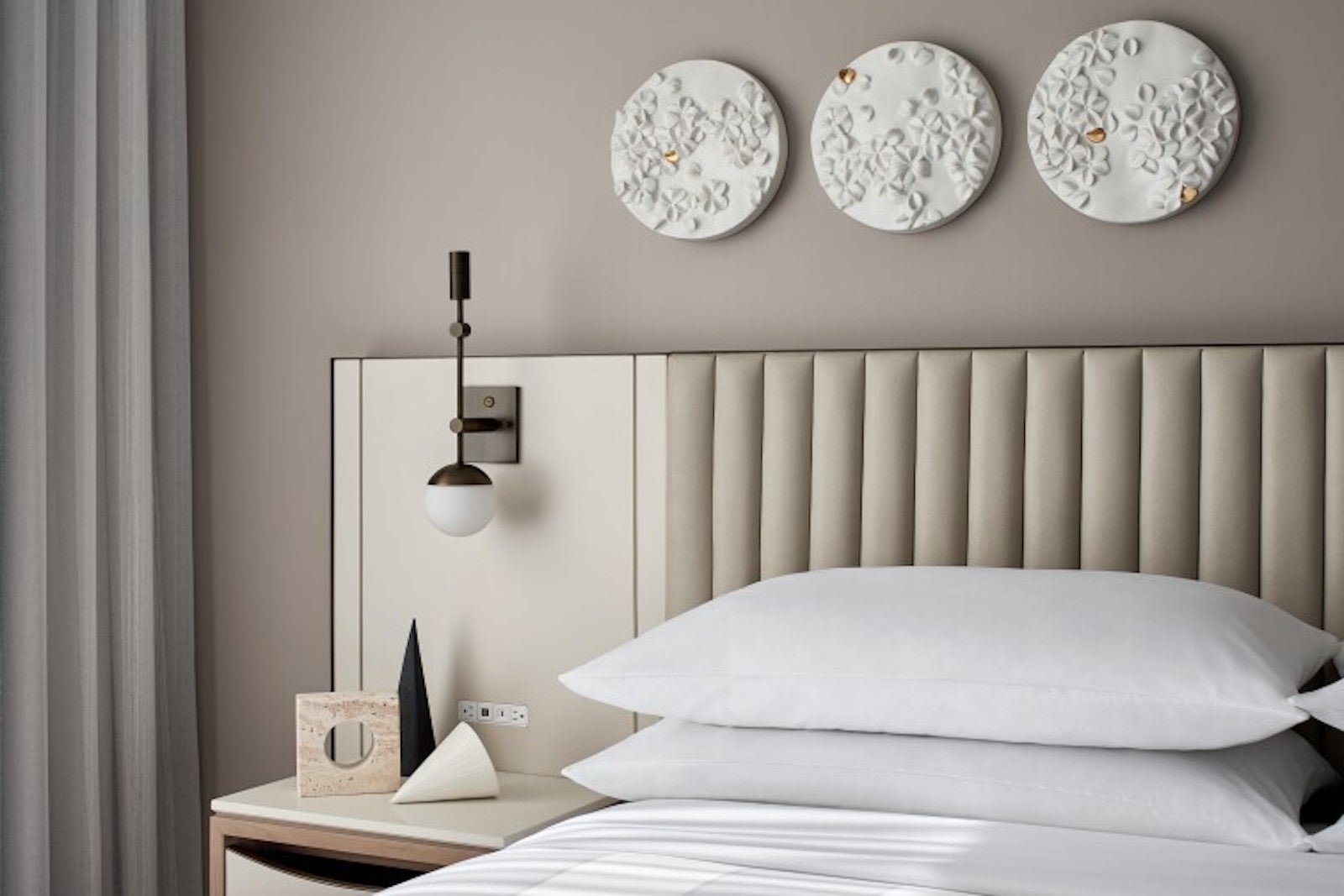 bed with padded headboard, nightstand, lamp and white plaster circles above bed