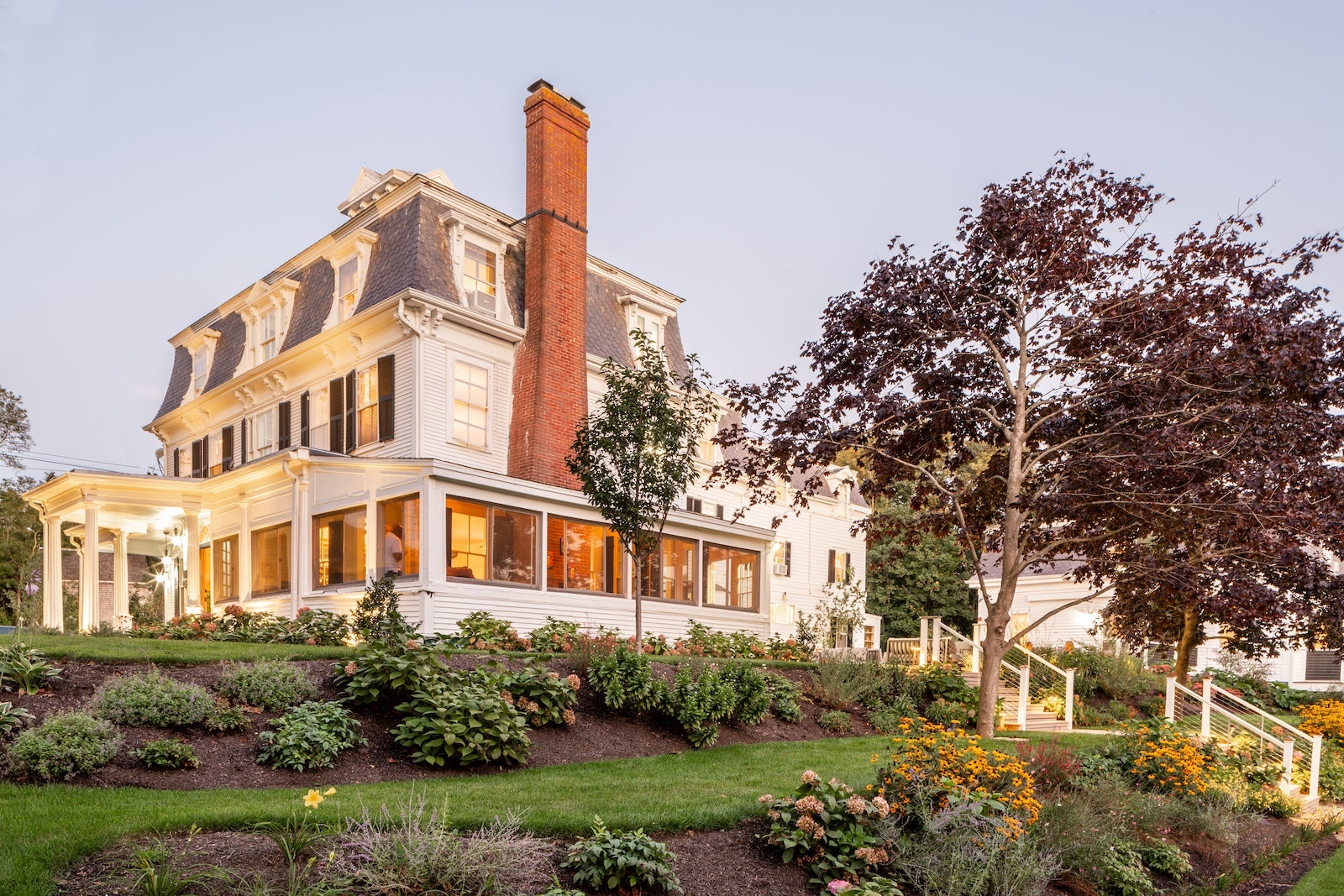 exterior photo of large white house with lush green yard