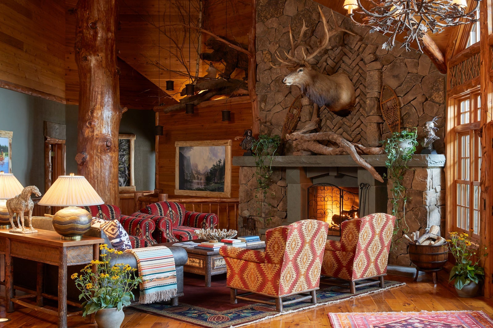 rustic-style living room with moose on wall, fireplace and chairs