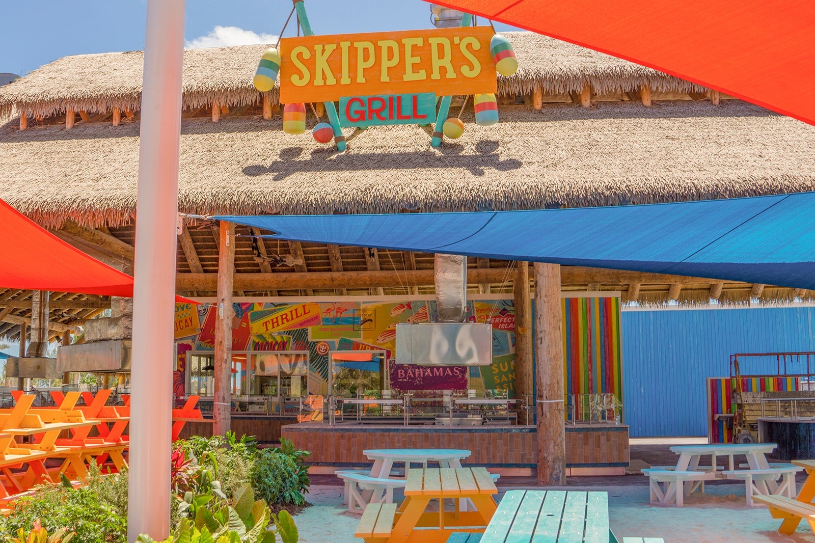 Outdoor restaurant with colorful signs and picnic tables on Royal Caribbean's CocoCay