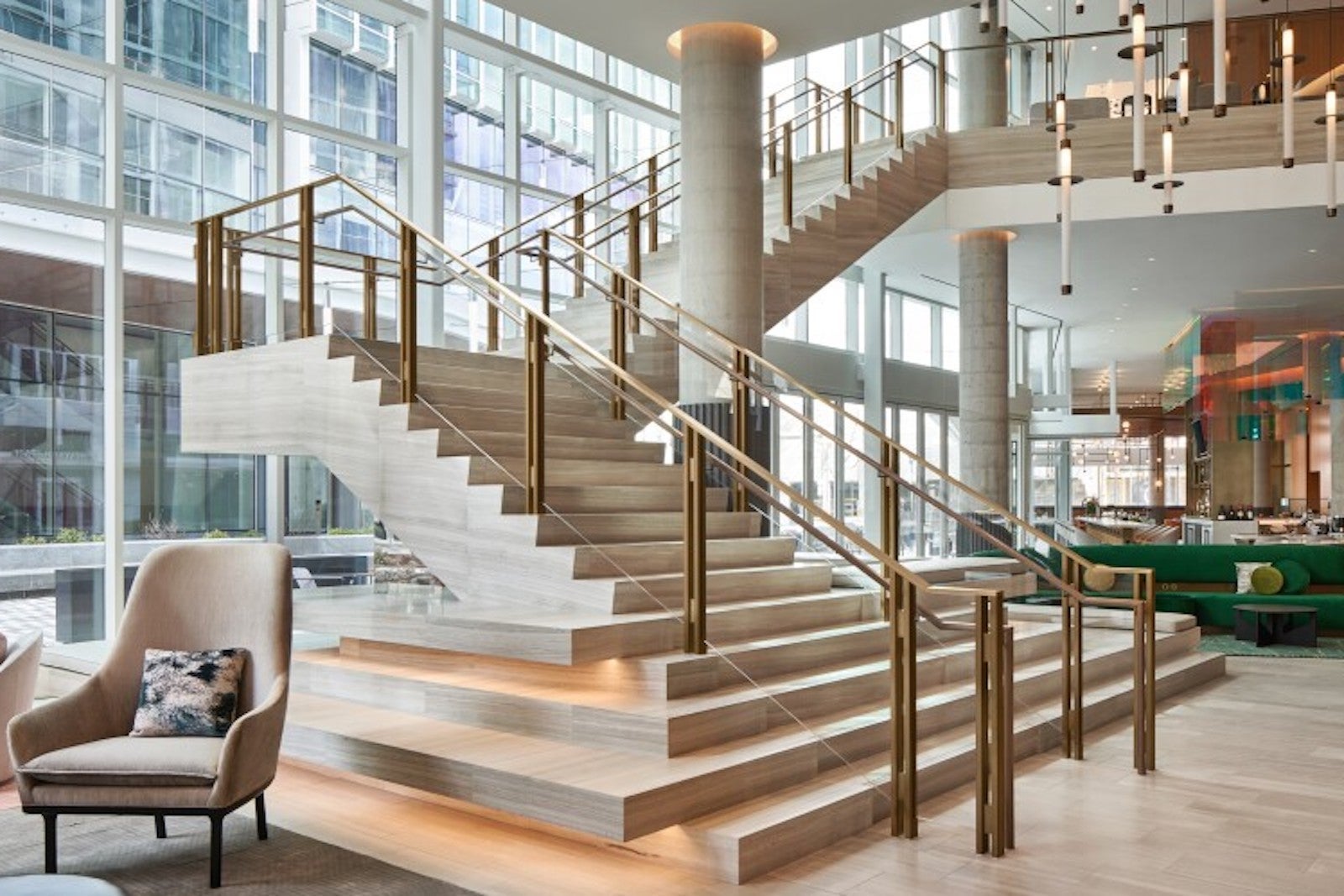 large hotel lobby with floating staircase, chairs and couches