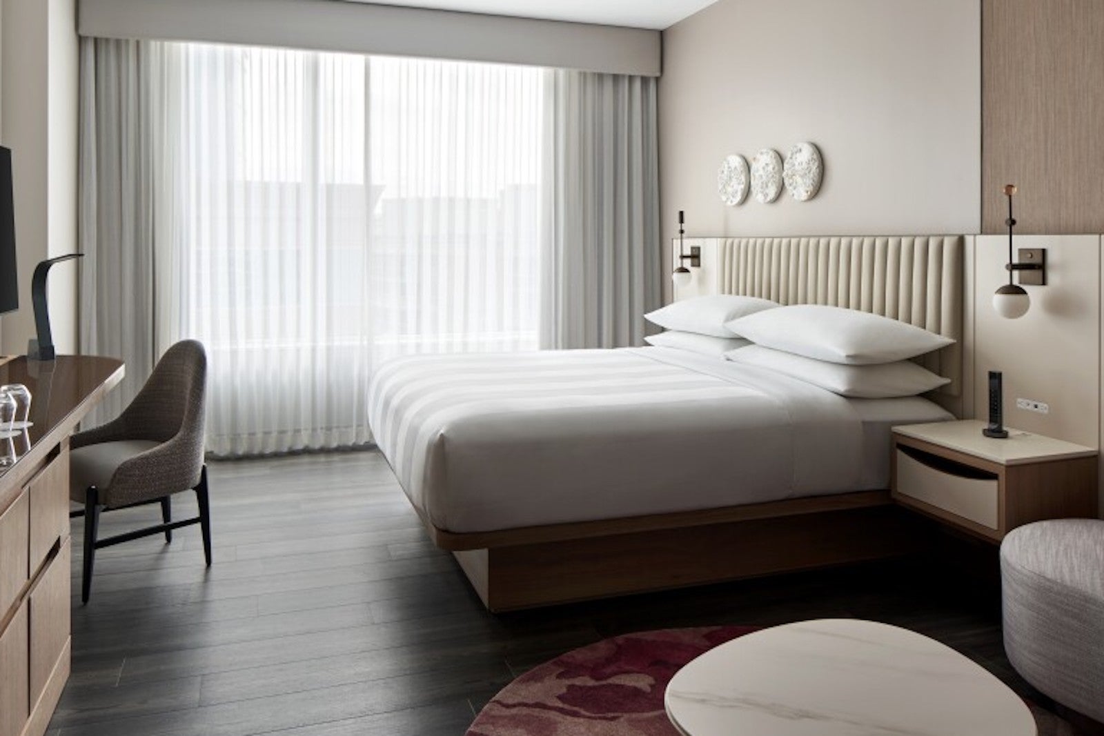white, airy hotel room with bed, desk, couch and chair