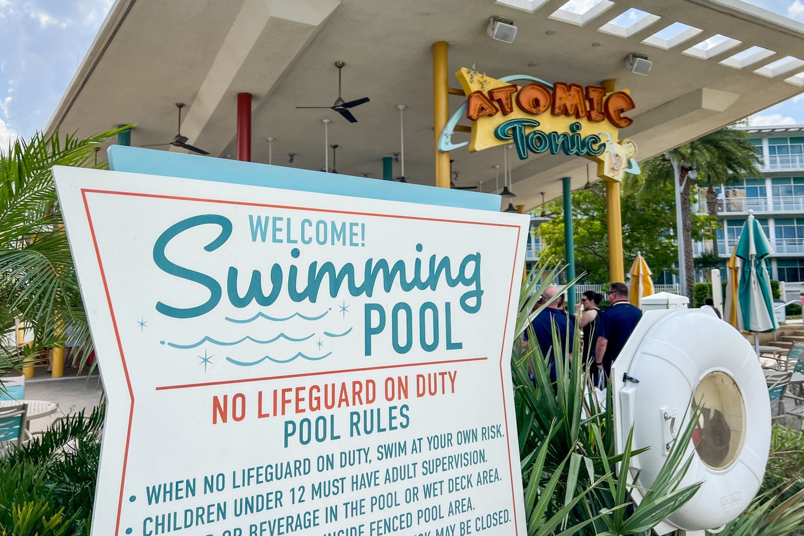 A sign detailing the pool rules with a bar in the background.