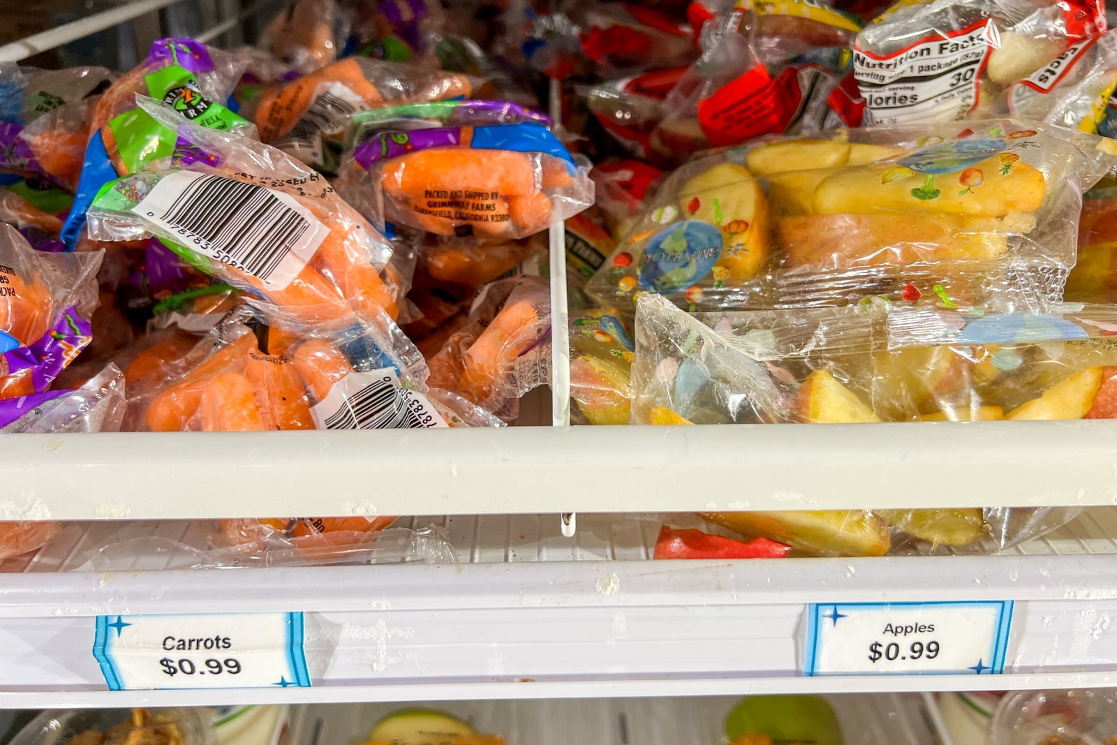 A fridge with kid's carrots and apple slices.