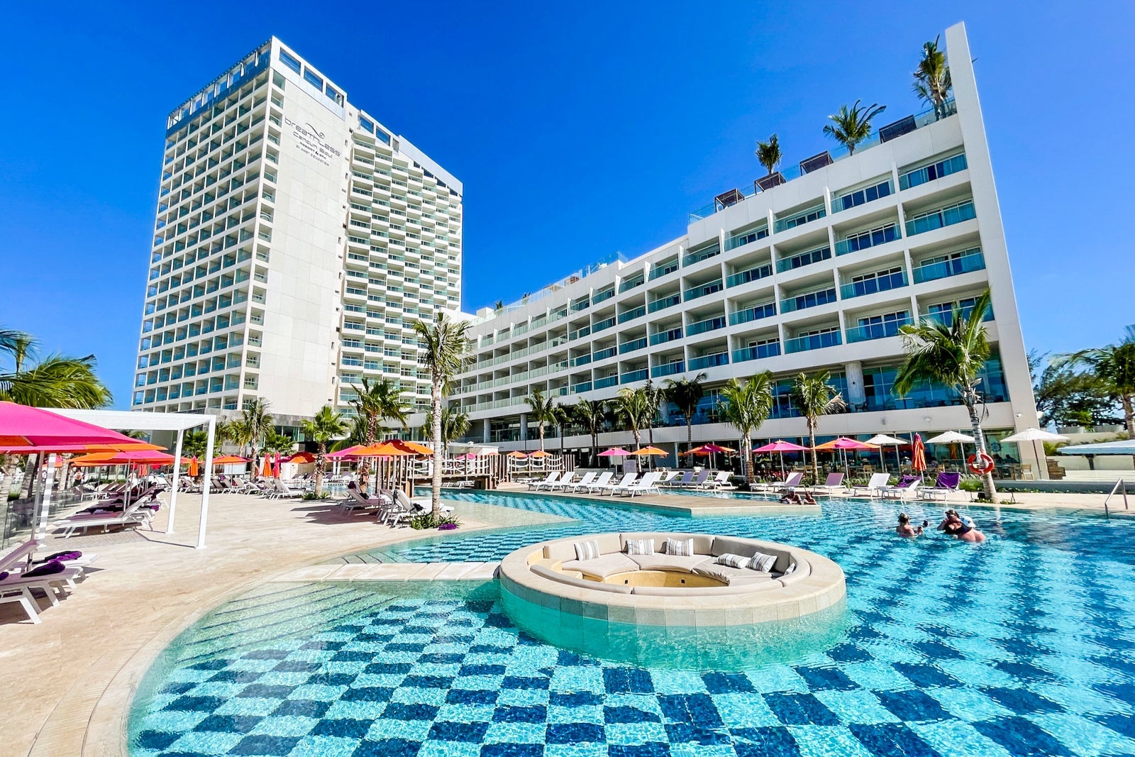 a hotel pool in foreground with large hotel towers in the background