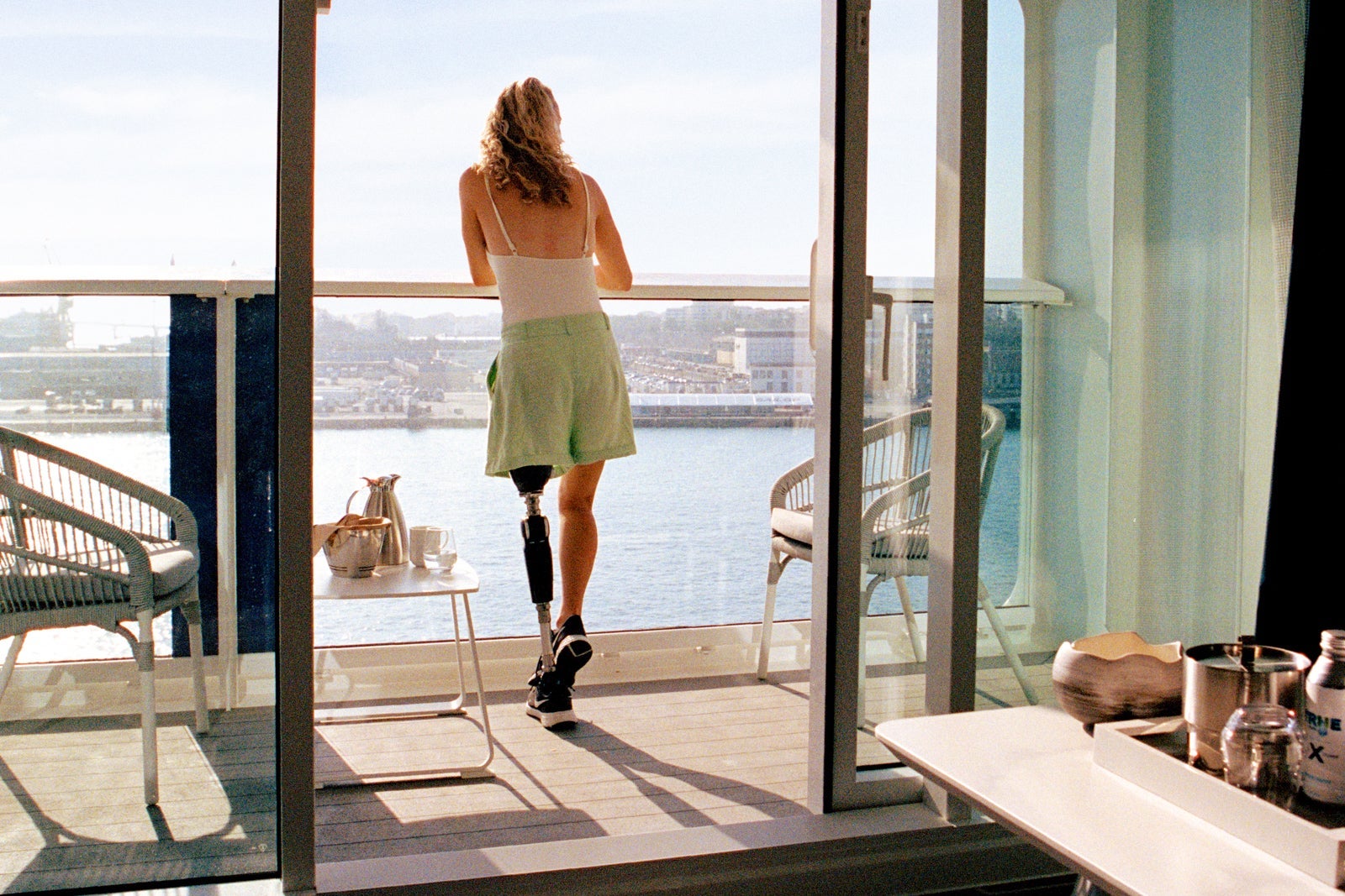 Woman with prosthetic leg leaning against cruise ship balcony railing