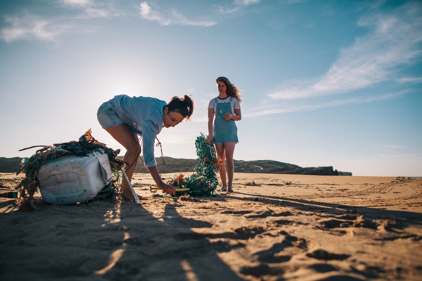 Women pick up litter on a beach