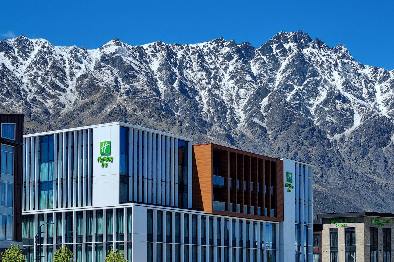modern, boxy hotel underneath large mountain range