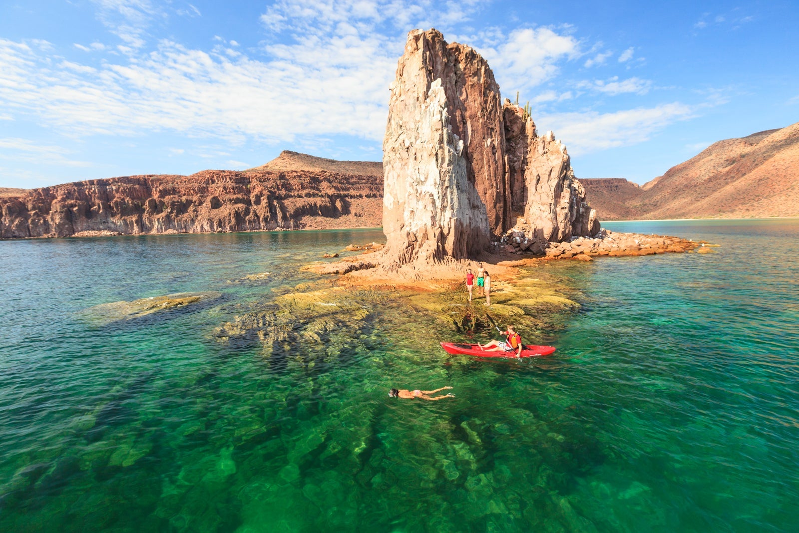 Kayakers and swimmers around a rock formation