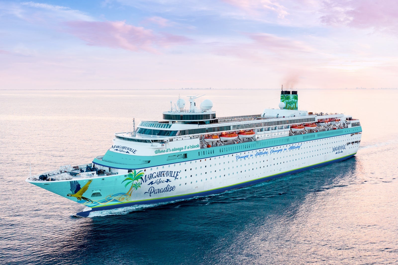 View of Margaritaville at Sea's Paradise cruise ship sailing on blue water with a pinkish-purple sky in the background