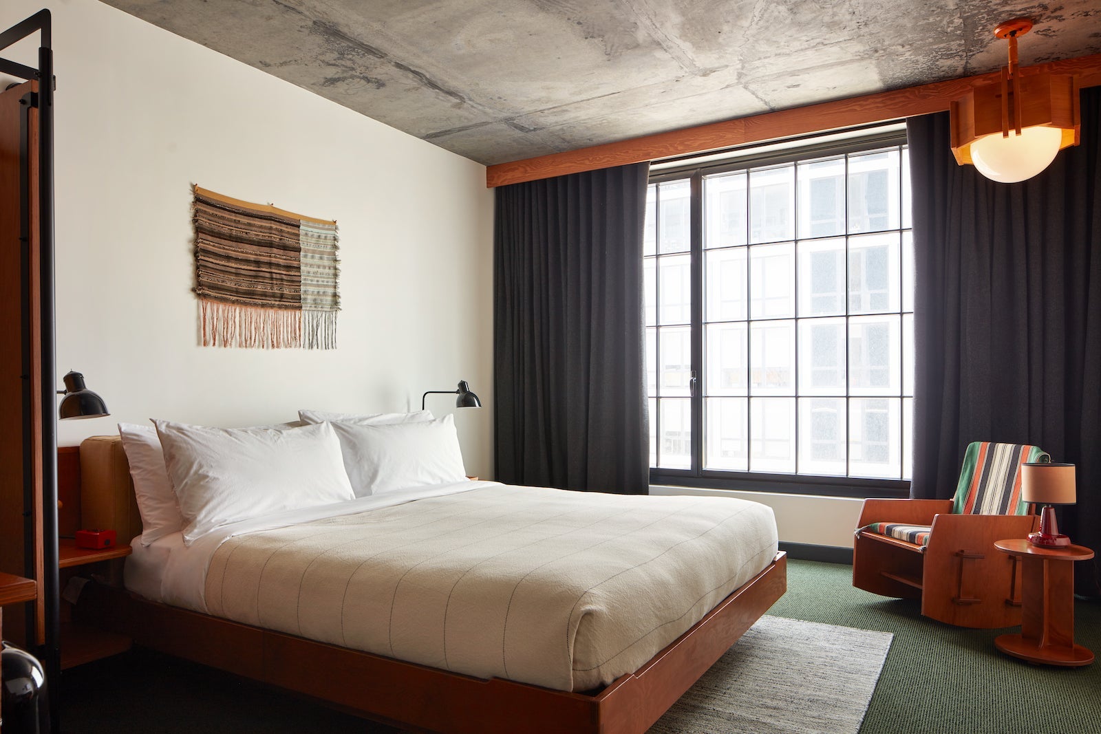hotel room with large windows, white bed and multi-color chair
