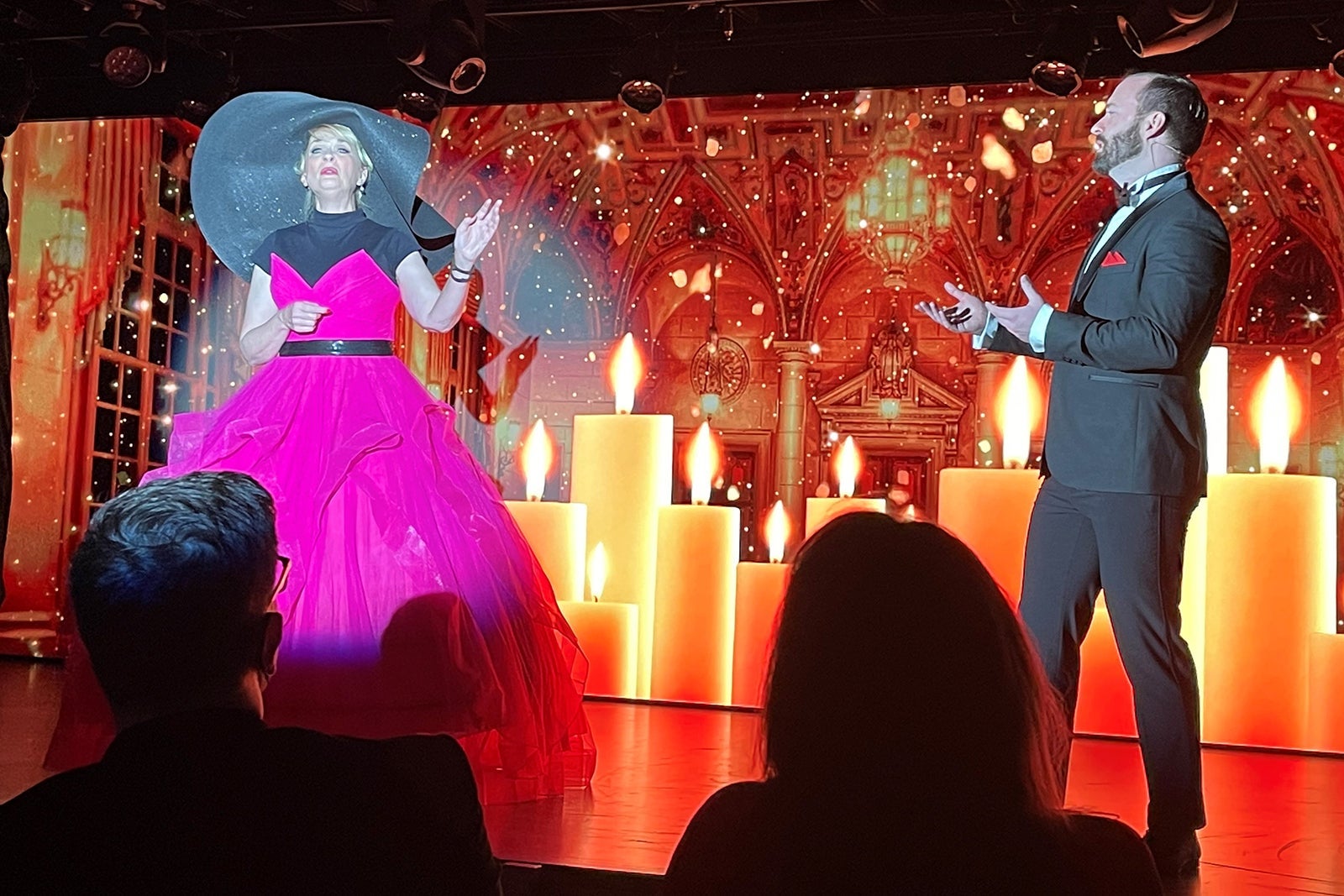 Cruise director in hot pink dress performs with man in suit