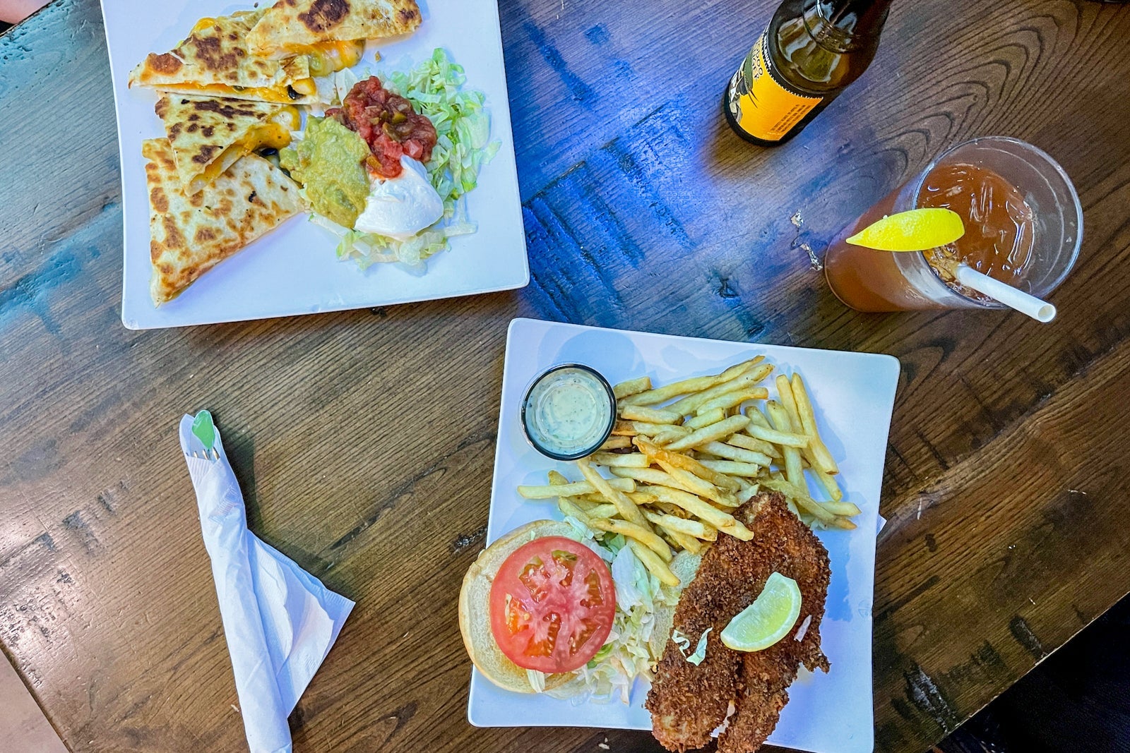 an overhead view of 2 plates, one with a quesadilla and another with a sandwich