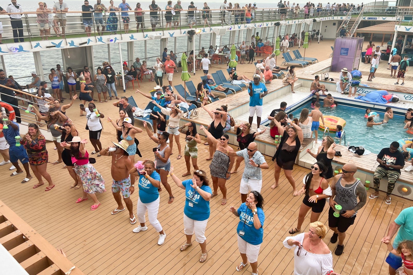 A crowd of passengers dancing on a cruise ship pool deck