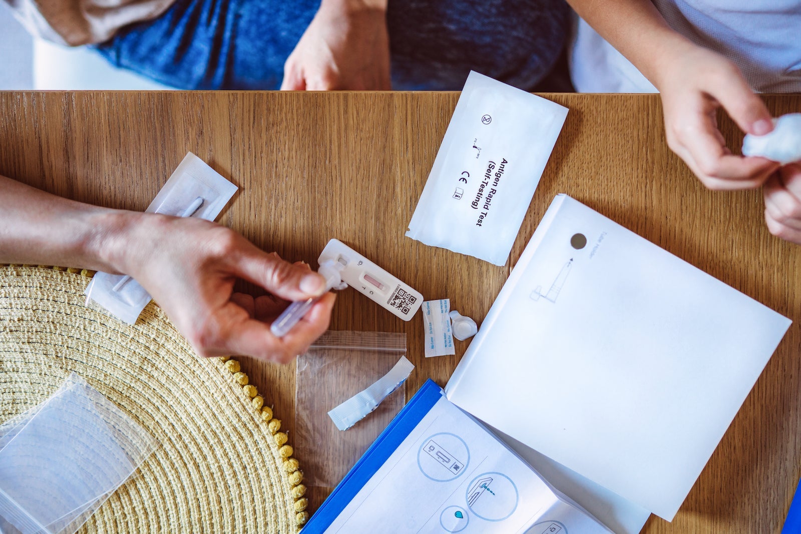 Directly above view of mom using Covid-19 rapid self-test kit for her kid at home