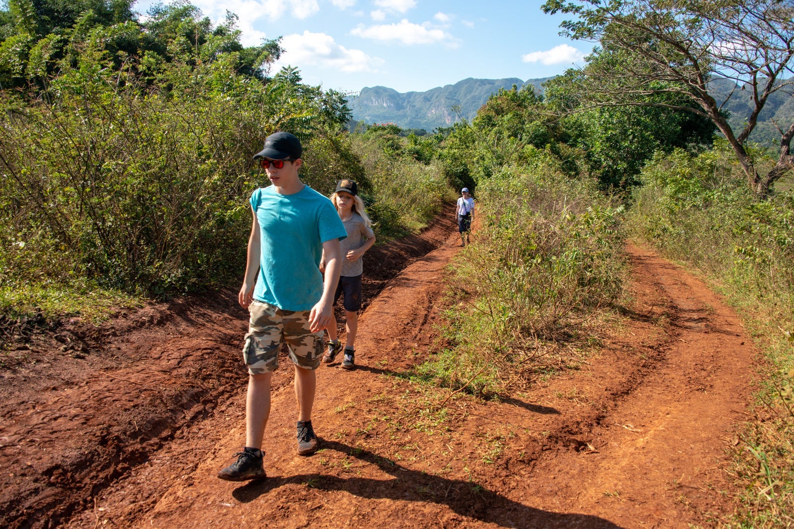 Hikers walking along a dirt trail surrounded by low shrubbery
