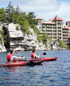 two people kayaking on lake in front of castle resort