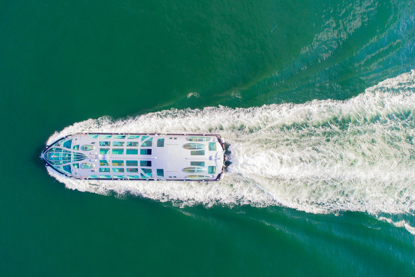 View of a pleasure craft from above as it sails through teal water